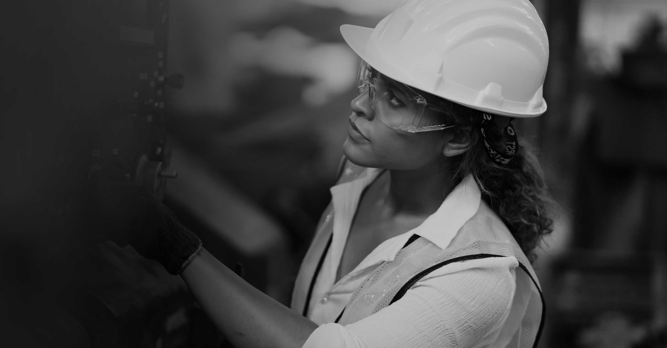 Woman with hard hat working on machinery 